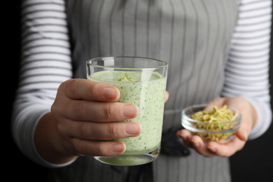 Photo of Woman holding green buckwheat smoothie, closeup view