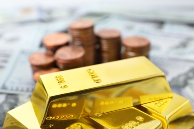 Photo of Shiny gold bars and coins on banknotes