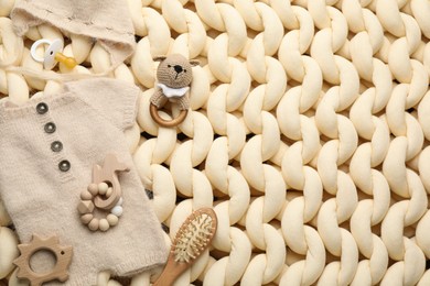 Photo of Different baby stuff on beige knitted blanket, flat lay. Space for text