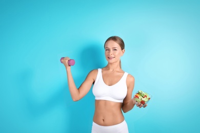 Photo of Slim woman with salad and dumbbell on color background. Healthy diet