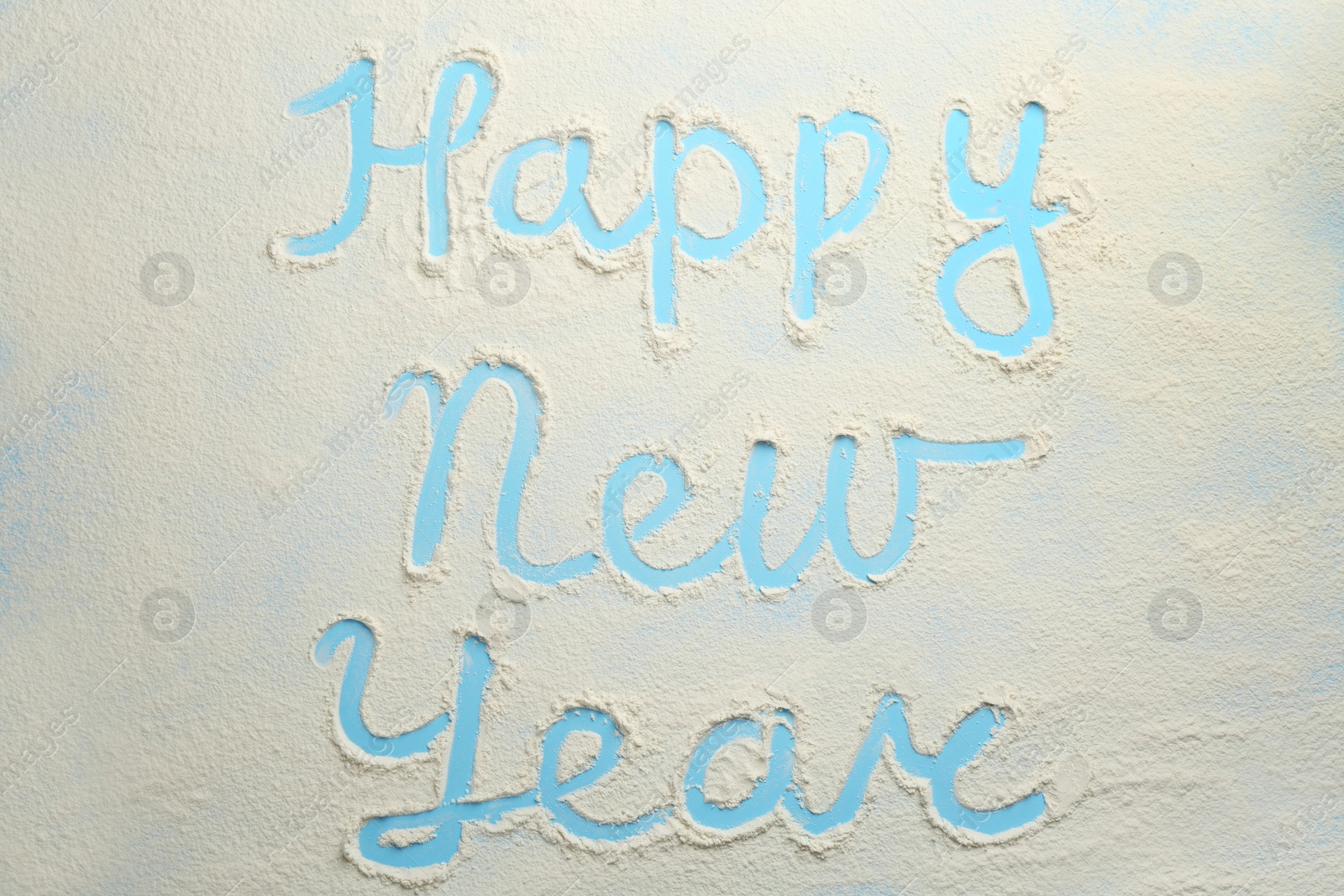 Photo of Phrase Happy New Year made of flour on light blue background, top view