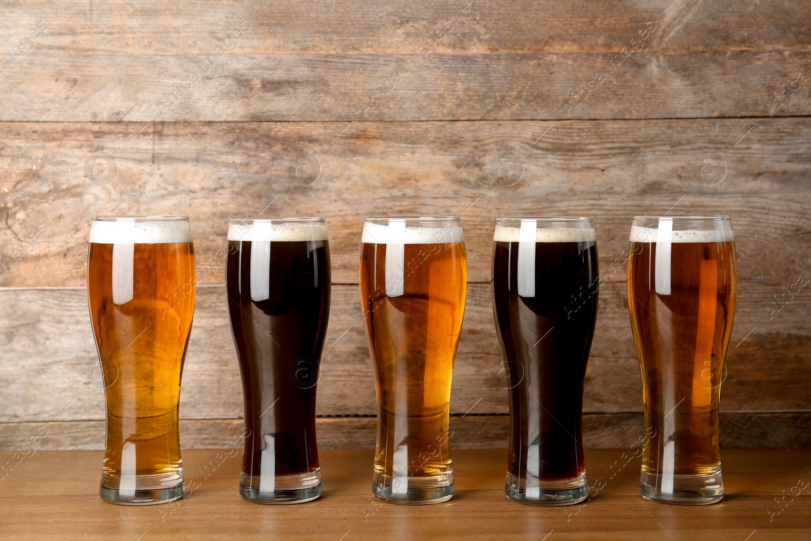 Photo of Glasses with beer on table against wooden background