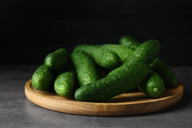 Photo of Wooden board with fresh ripe cucumbers on dark grey table