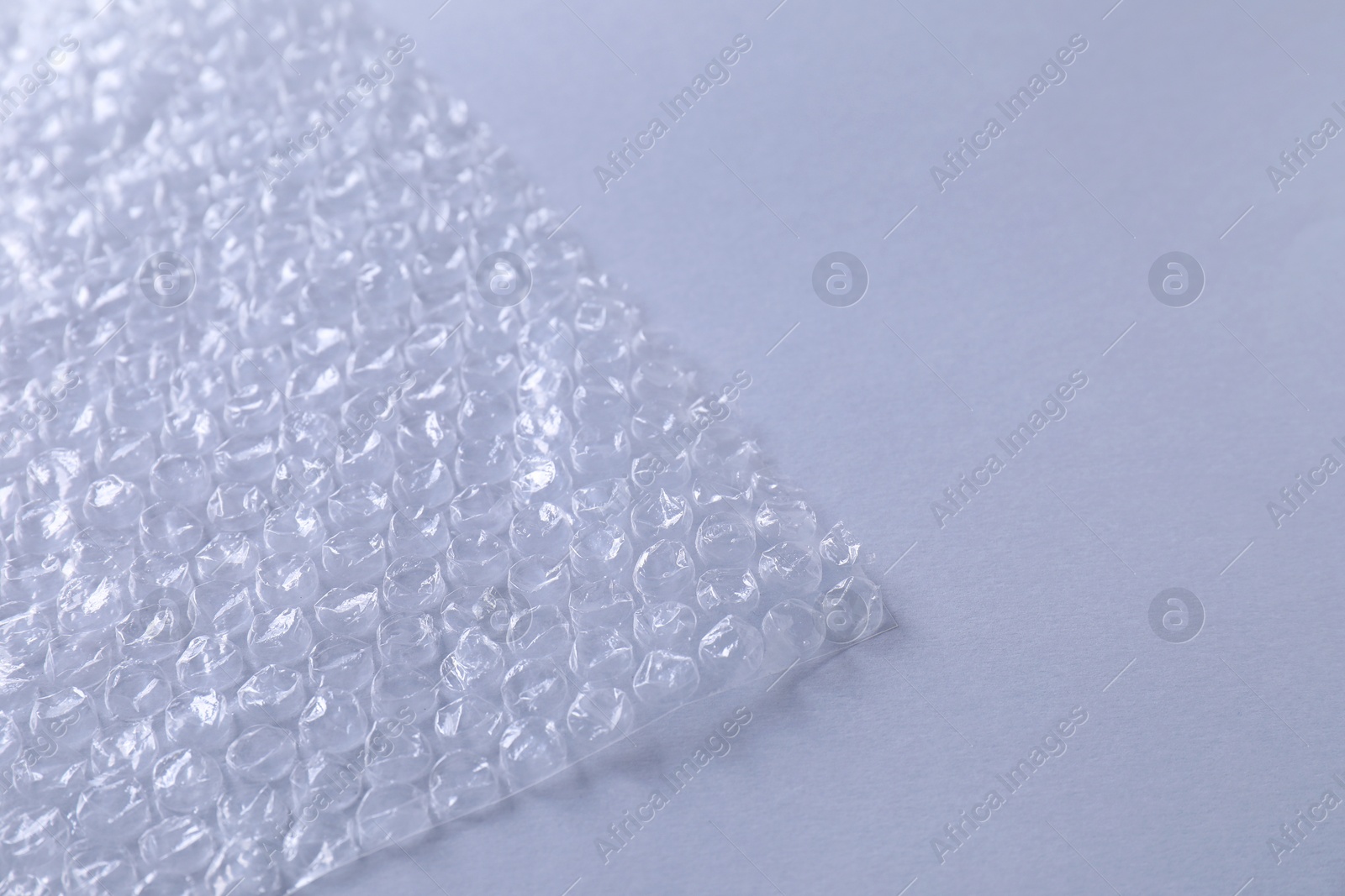 Photo of Transparent bubble wrap on gray background, closeup. Space for text