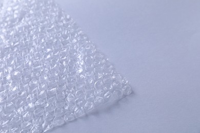 Transparent bubble wrap on gray background, closeup. Space for text