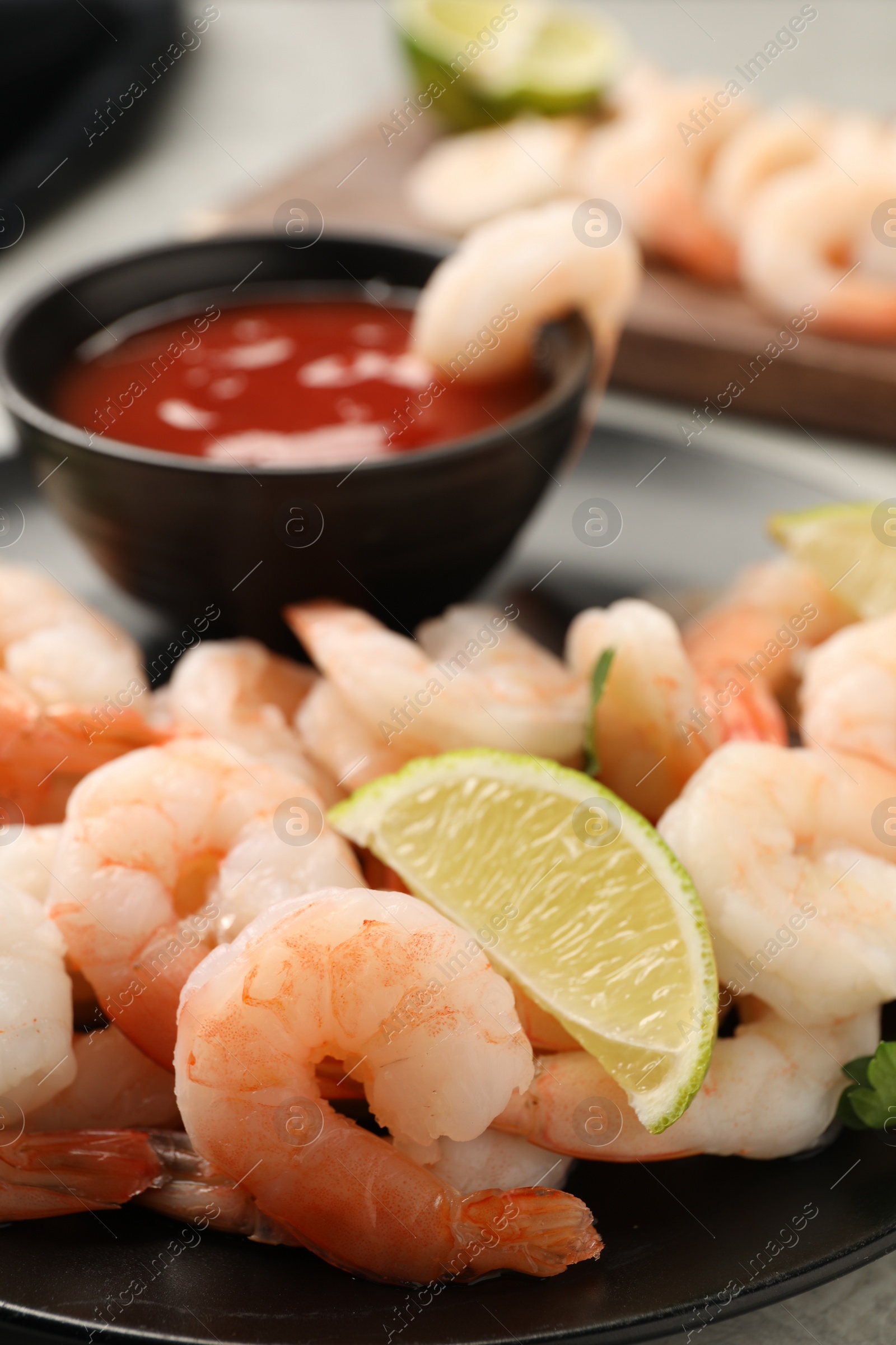 Photo of Tasty boiled shrimps with cocktail sauce, parsley and lime on table, closeup