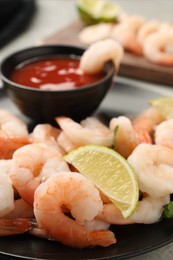 Tasty boiled shrimps with cocktail sauce, parsley and lime on table, closeup