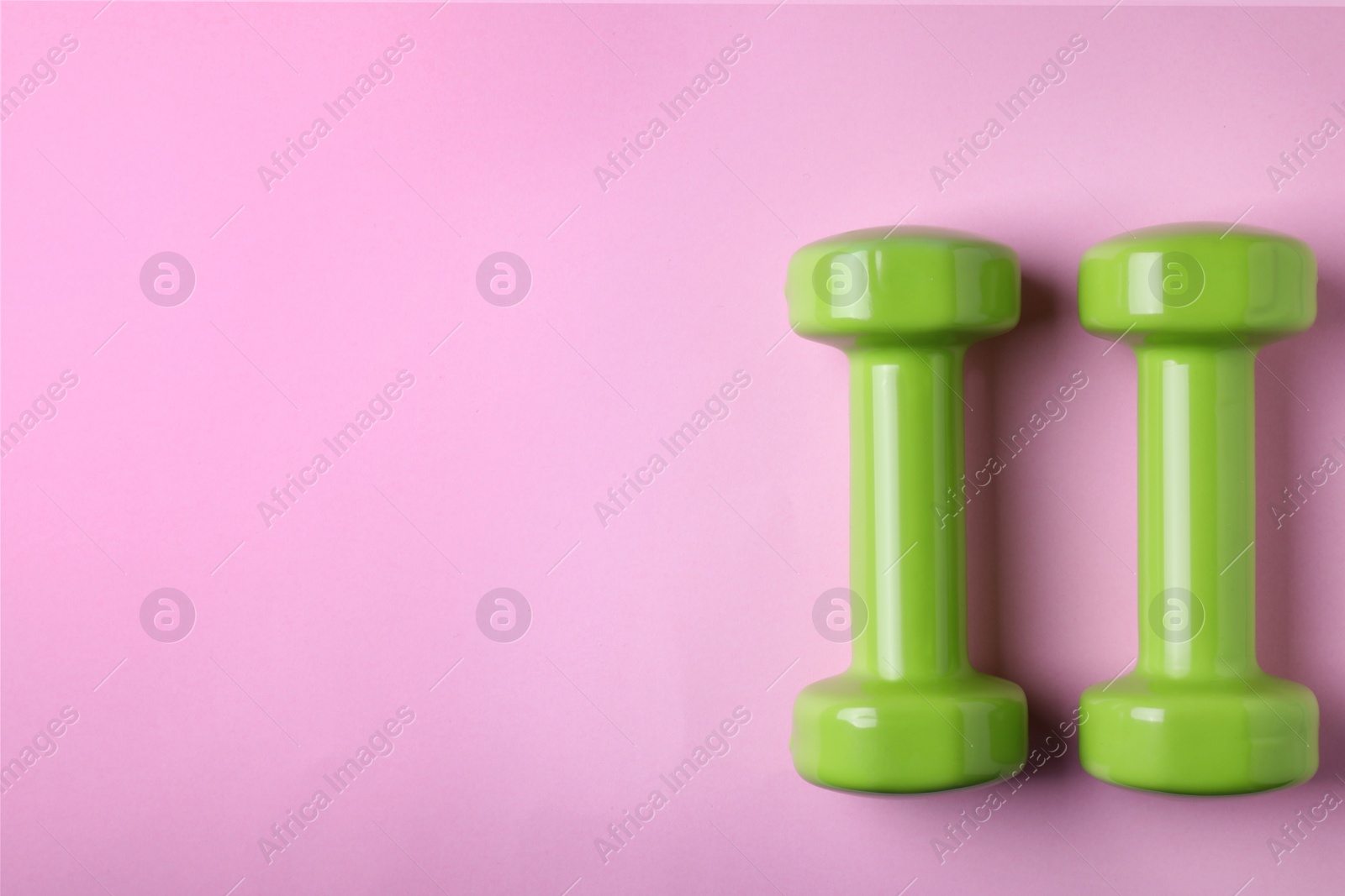 Photo of Bright dumbbells and space for text on color background, flat lay. Home fitness