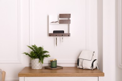 Photo of Wooden hanger for keys on white wall in hallway