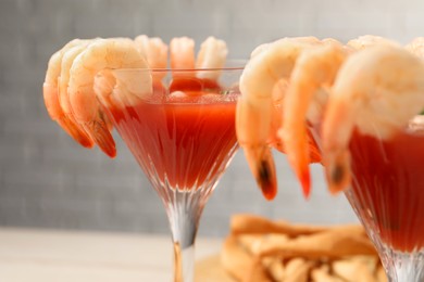 Tasty shrimp cocktail with sauce in glasses on table, closeup