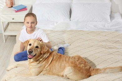 Photo of Cute child with her Labrador Retriever on bed at home. Adorable pet