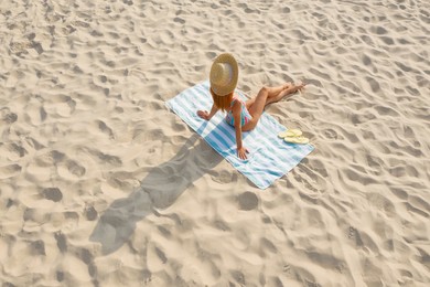 Image of Woman sunbathing on beach towel at sandy coast