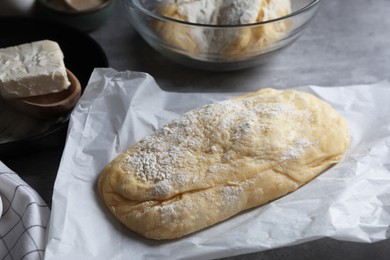 Photo of Raw dough for ciabatta and flour on grey table