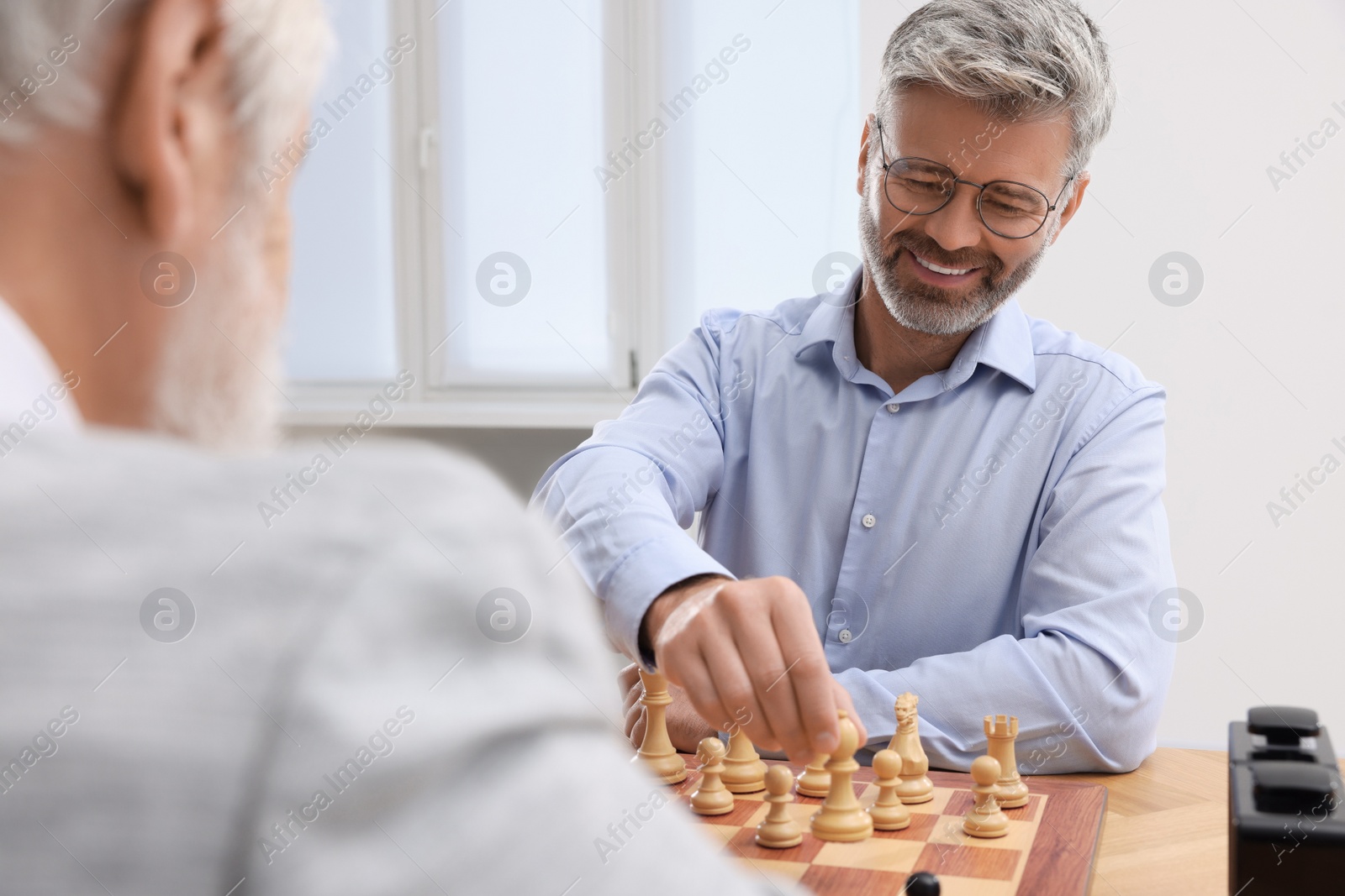 Photo of Men playing chess during tournament at table indoors