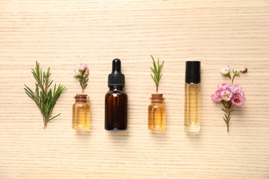 Photo of Flat lay composition with bottles of natural tea tree oil on wooden background