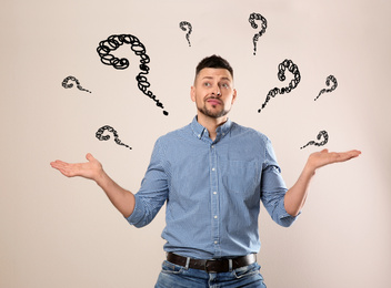 Emotional man with drawings of question marks on white background