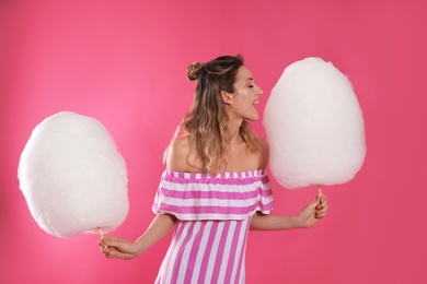 Portrait of pretty young woman with cotton candy on pink background