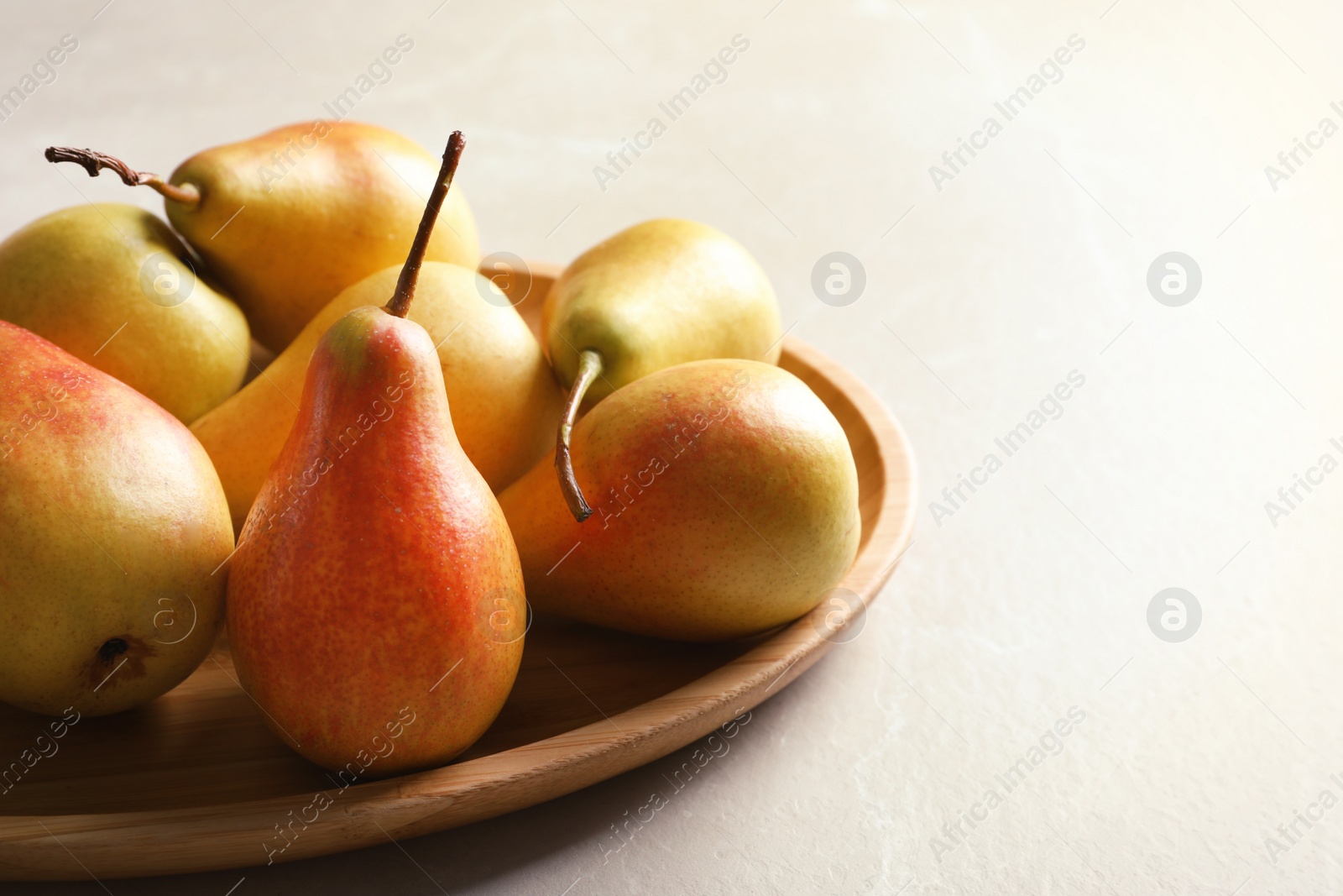 Photo of Plate with ripe pears on light background, closeup. Space for text