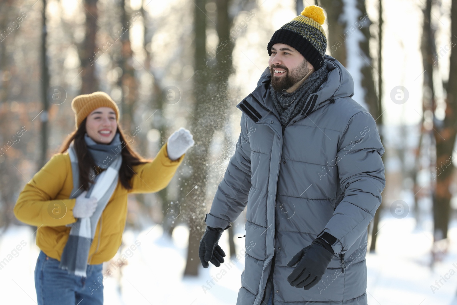 Photo of Happy couple playing snowballs on winter day outdoors