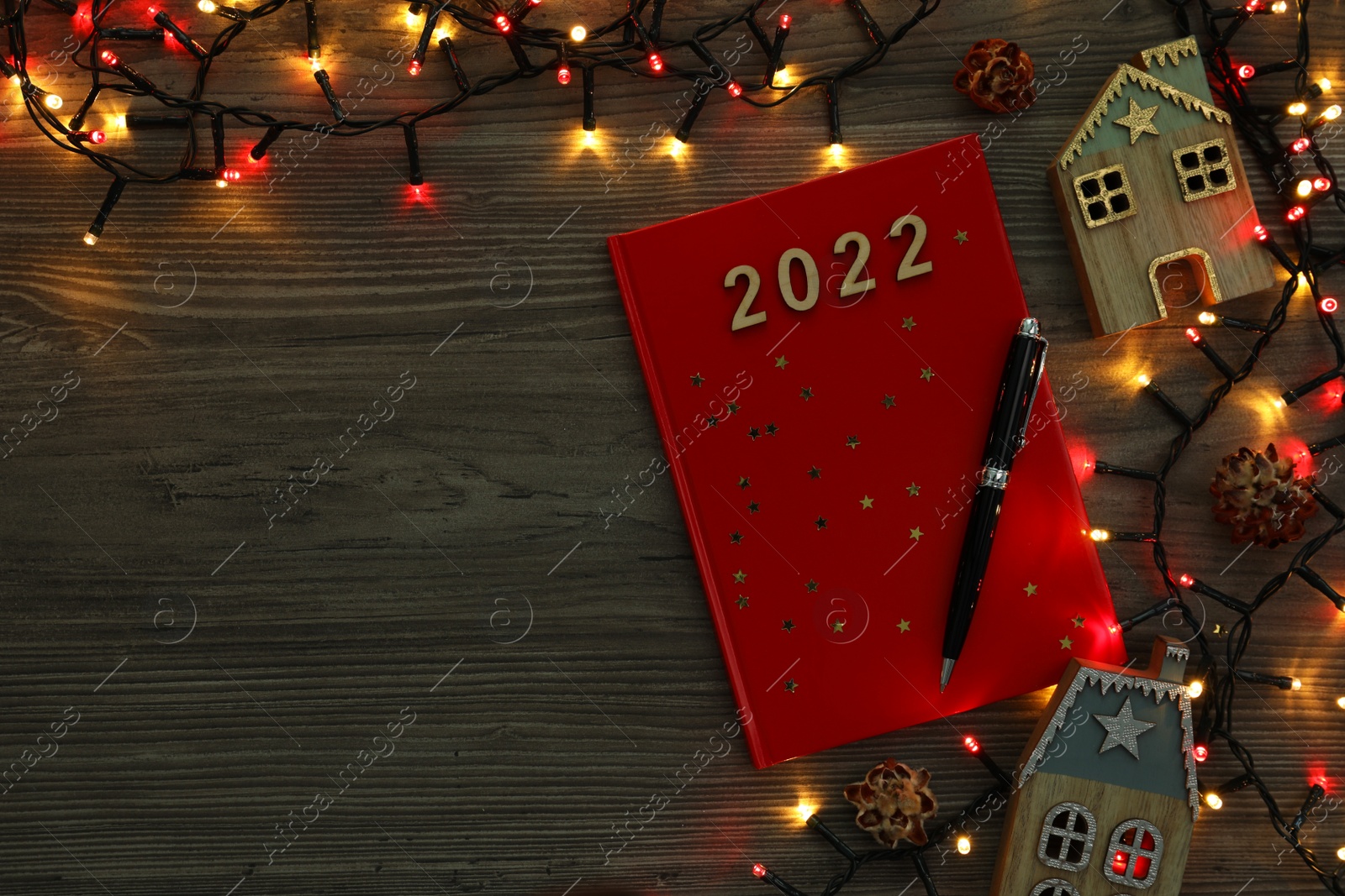 Photo of Red planner and Christmas decor on wooden background, flat lay with space for text. 2022 New Year aims