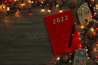 Photo of Red planner and Christmas decor on wooden background, flat lay with space for text. 2022 New Year aims