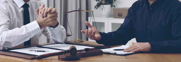 Image of Lawyer working with client at wooden table in office, closeup. Banner design