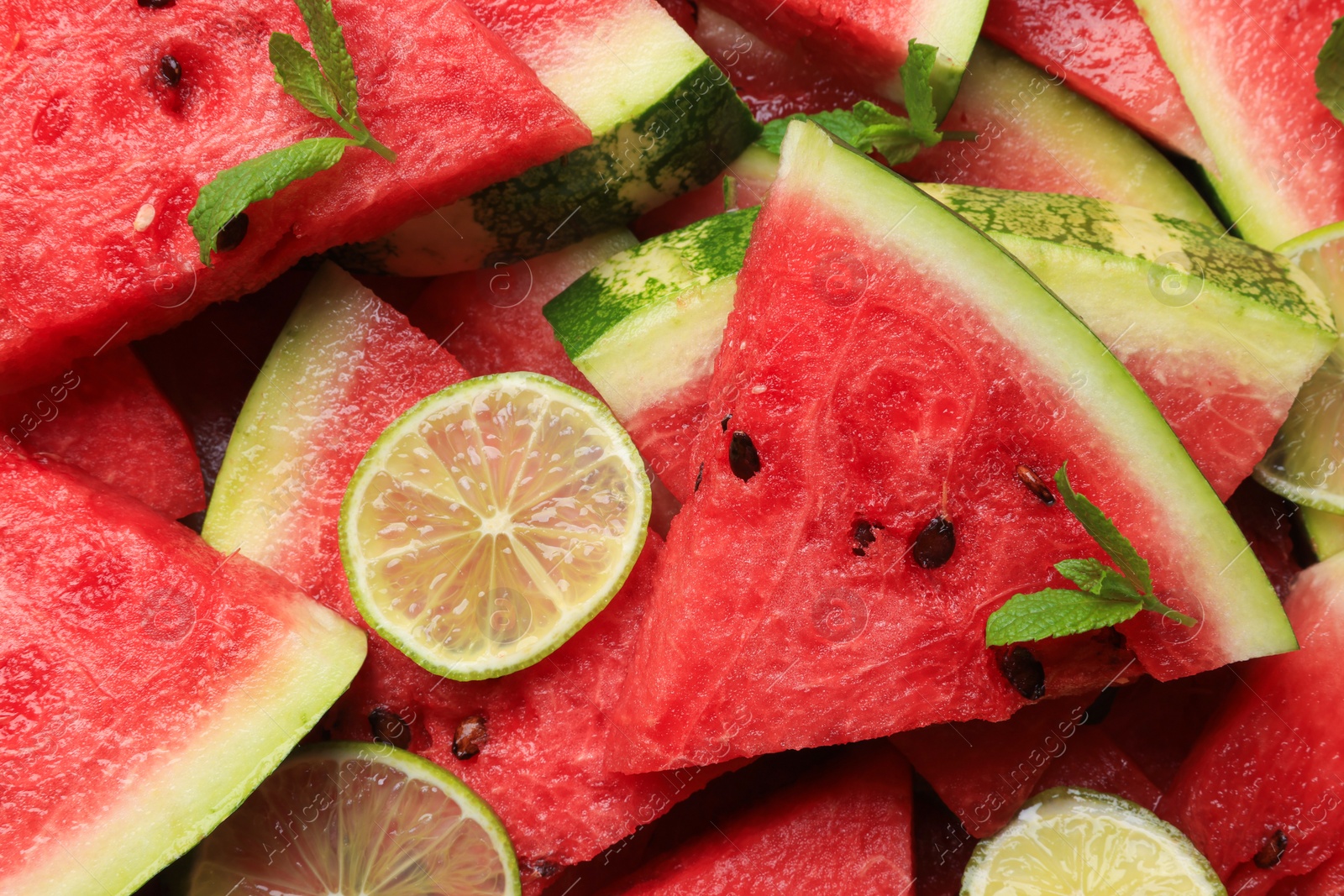 Photo of Slices of juicy watermelon with lime and mint as background, top view