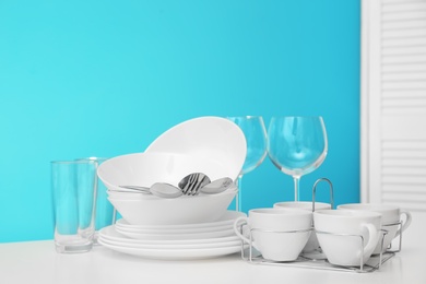 Set of clean dishware on table against color background