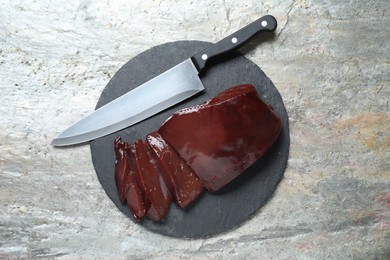 Photo of Cut raw beef liver and knife on grey table, top view