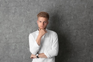 Portrait of handsome young man near grey wall