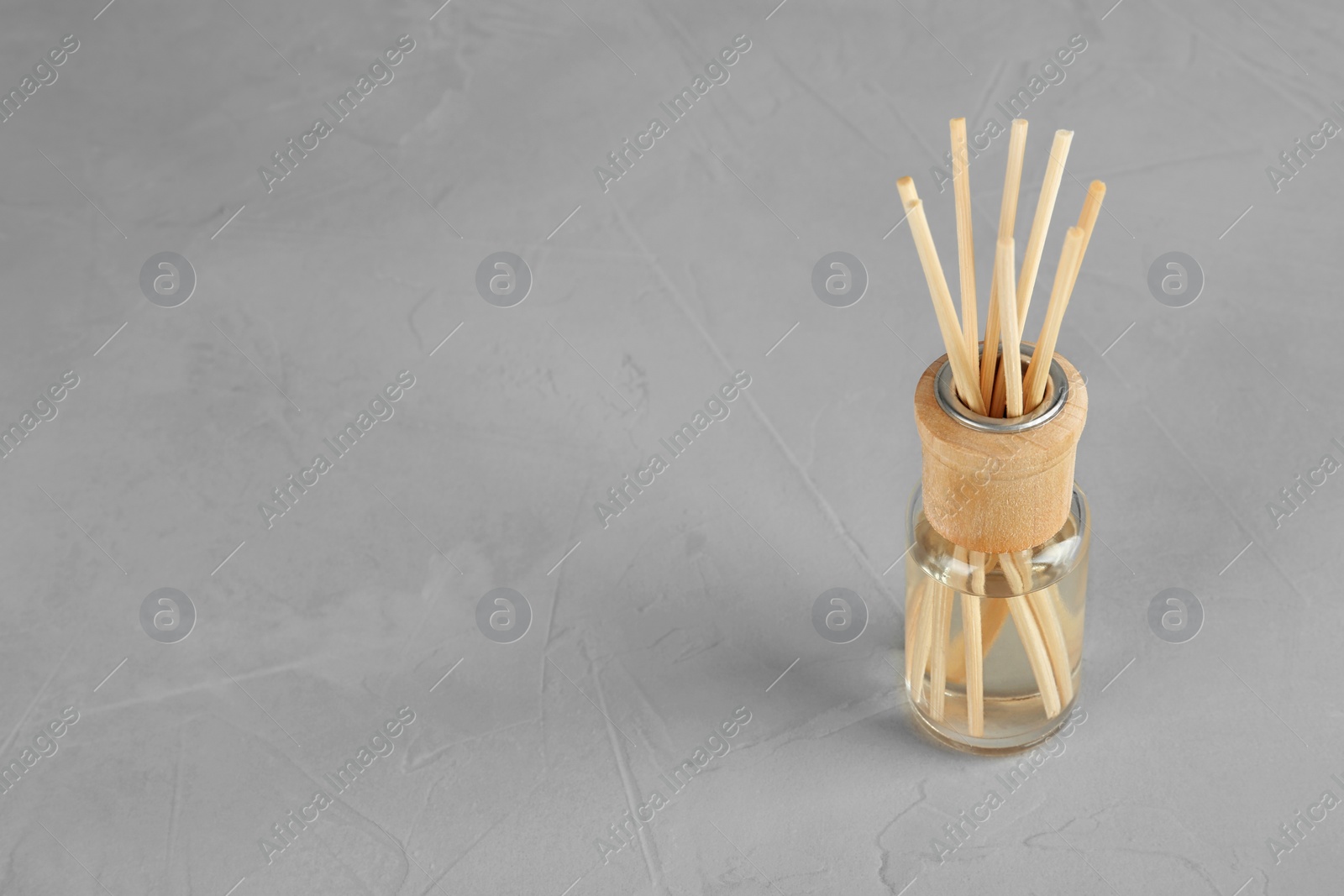Photo of Aromatic reed freshener on grey table, space for text