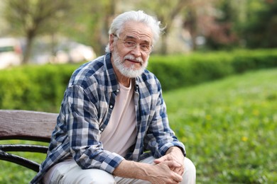 Portrait of happy grandpa with glasses on bench in park