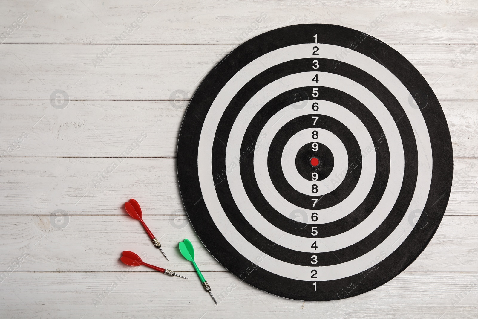 Photo of Dart board with color arrows on white wooden background, top view. Space for text