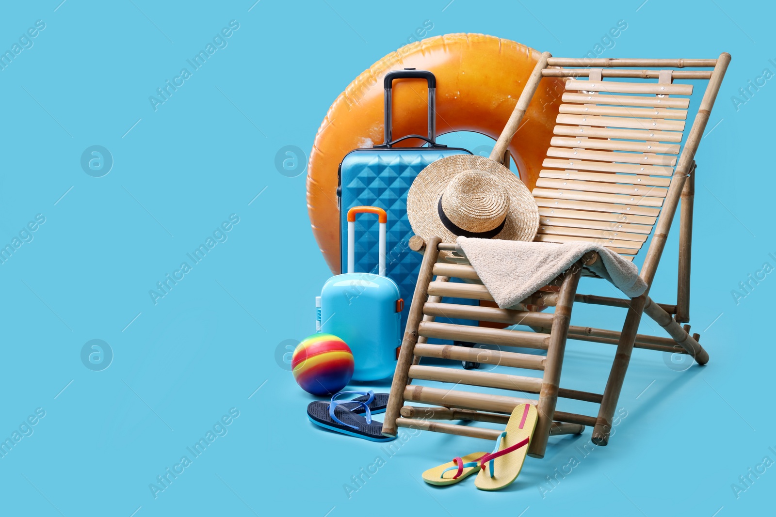 Photo of Deck chair, suitcases and beach accessories on light blue background, space for text. Summer vacation