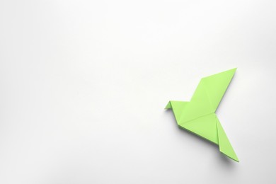 Photo of Beautiful light green origami bird on white background, top view. Space for text