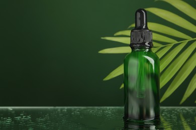 Photo of Bottleface serum and tropical leaf on wet surface against green background, closeup. Space for text