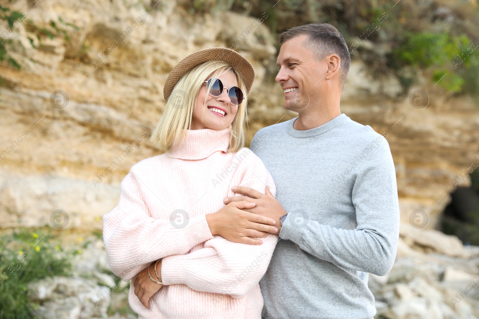 Photo of Happy couple in stylish sweaters near old cliff