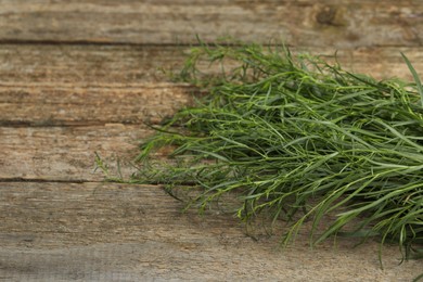 Photo of Fresh tarragon sprigs on wooden table, closeup. Space for text