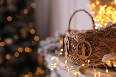 Photo of Fireplace mantel with wicker basket and Christmas lights against blurred background. Interior element