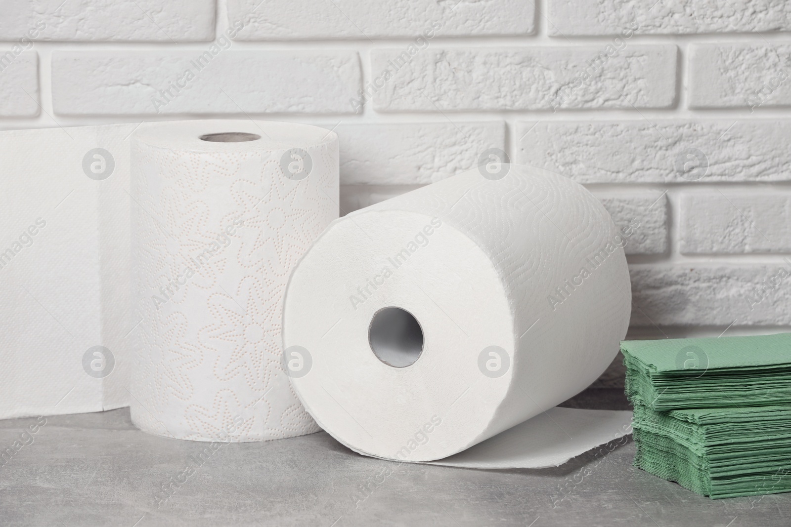 Photo of Different paper towels and napkins on grey table near white brick wall