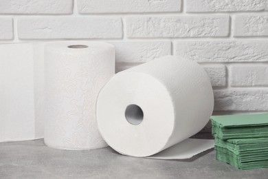 Different paper towels and napkins on grey table near white brick wall