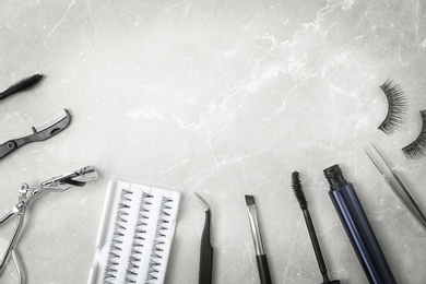 Flat lay composition with false eyelashes and cosmetic tools on light background