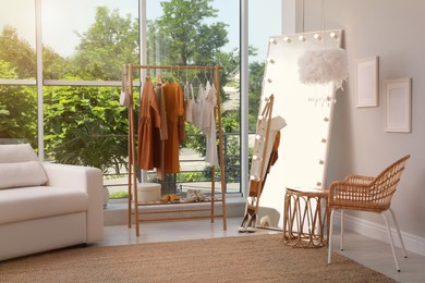 Photo of Dressing room interior with clothing rack and comfortable furniture