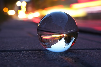 Beautiful city street, overturned reflection. Crystal ball on asphalt road outdoors, closeup