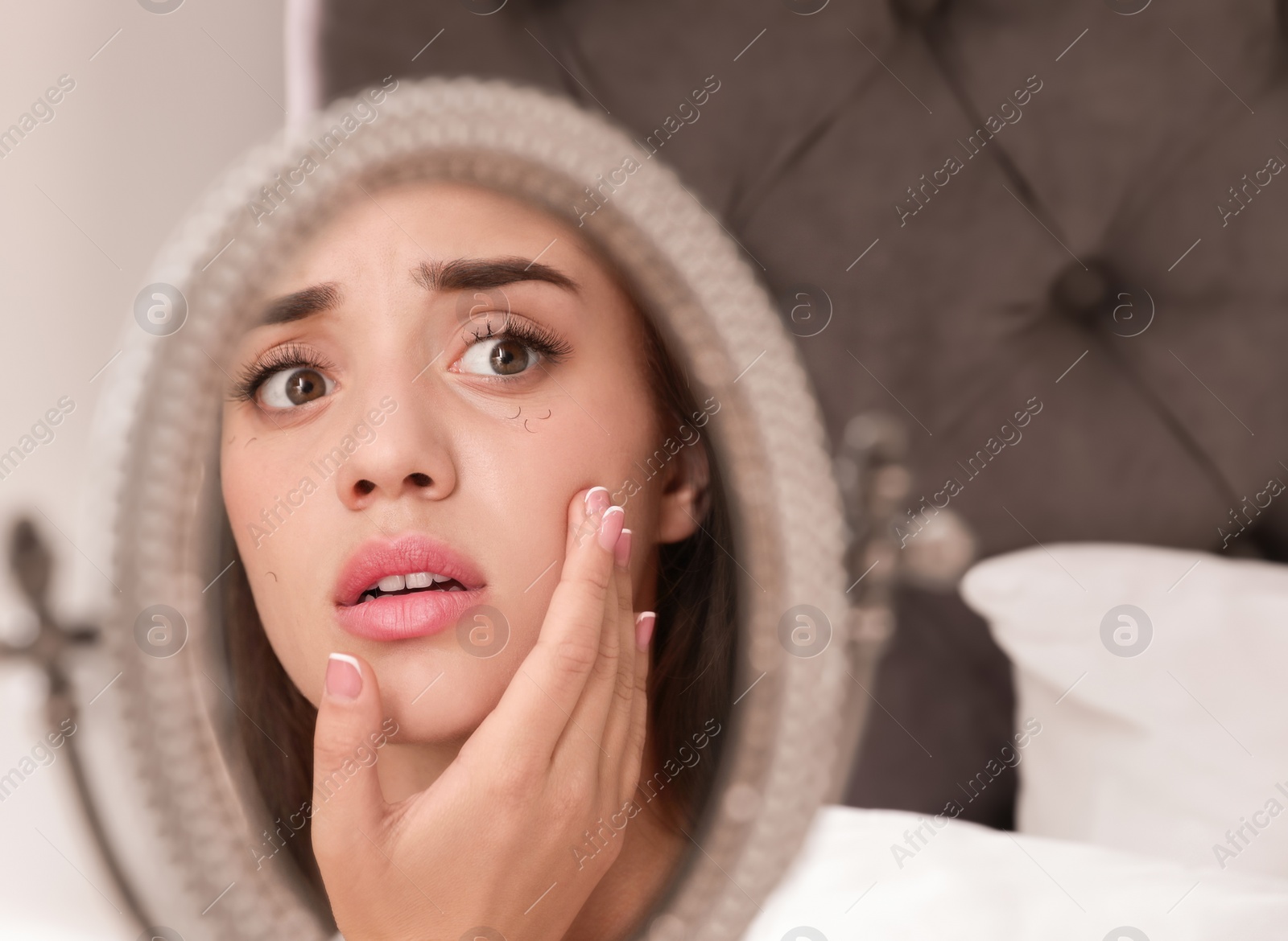 Photo of Young woman with eyelash loss problem looking in mirror indoors