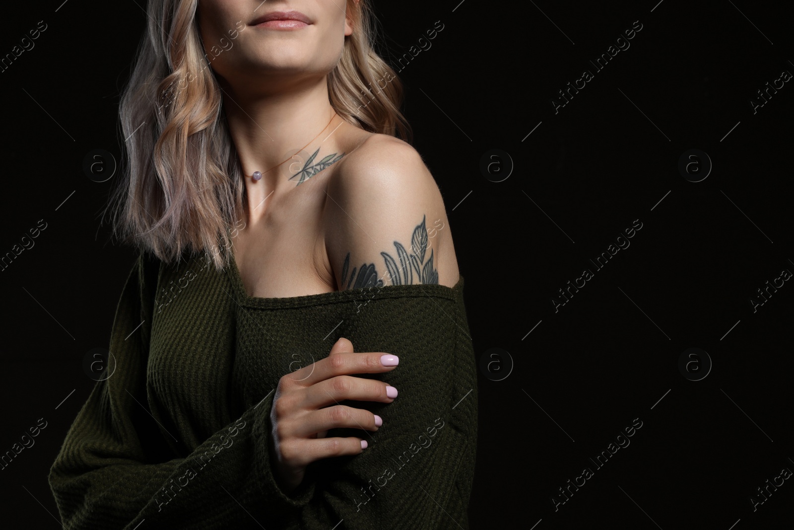 Photo of Beautiful woman with tattoos on body against black background, closeup. Space for text