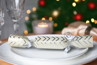 White plate with Christmas cracker on table, closeup