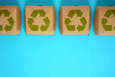 Paper boxes with recycling symbols on turquoise background, flat lay. Space for text