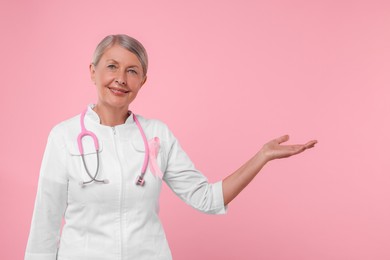 Photo of Doctor with pink ribbon and stethoscope on color background. Breast cancer awareness