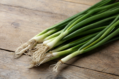 Fresh green spring onions on wooden table, closeup